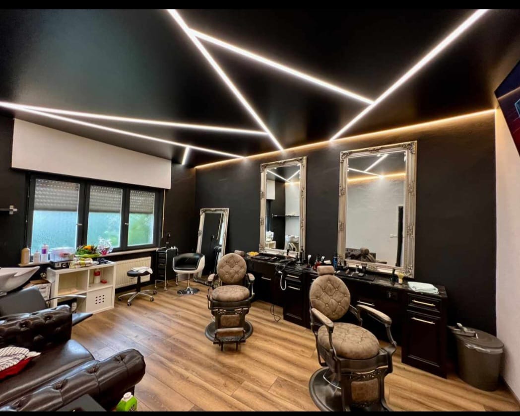 Schwarze Spanndecke mit LED-Liniendesign im Friseursalon